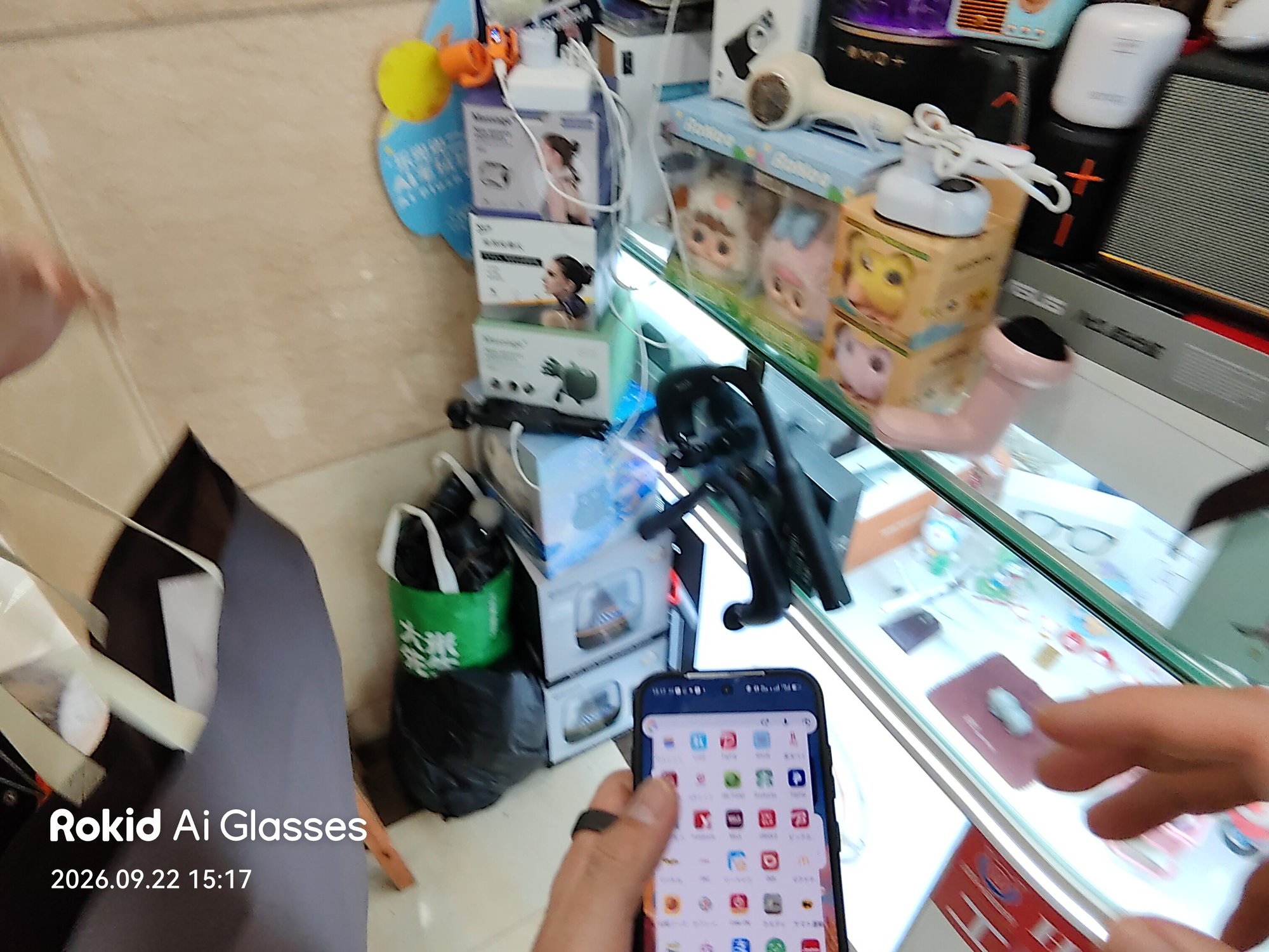 ガジェット店のショーケース前でスマホを操作する手元
