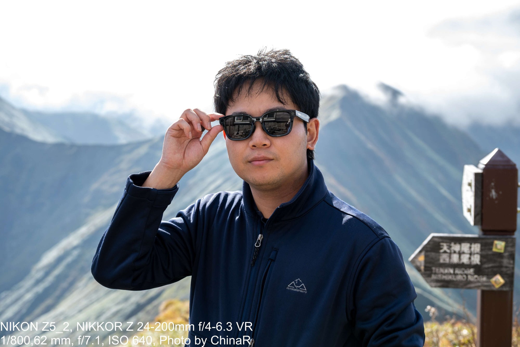 Rokid Ai Glasses Styleのつるに手をかけたカット。後ろに天神尾根・西黒尾根の道標