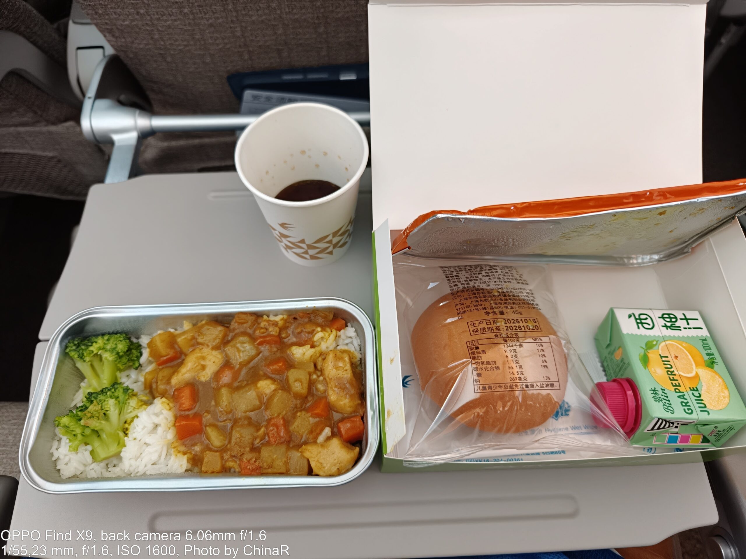 MU5595の機内食。カレー風の煮込みご飯とパン、グレープフルーツジュース